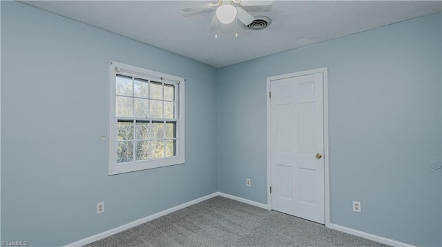 empty room featuring ceiling fan and carpet