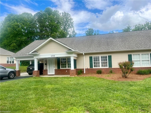 258 S Boyles St, Pilot Mountain, NC 27041 - view of front facade featuring brick siding, an attached carport, a front yard, a shingled roof, and a porch