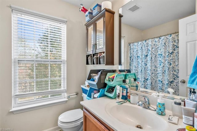 bathroom with plenty of natural light, toilet, and vanity