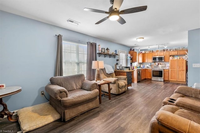 living room featuring rail lighting, ceiling fan, and dark wood-type flooring