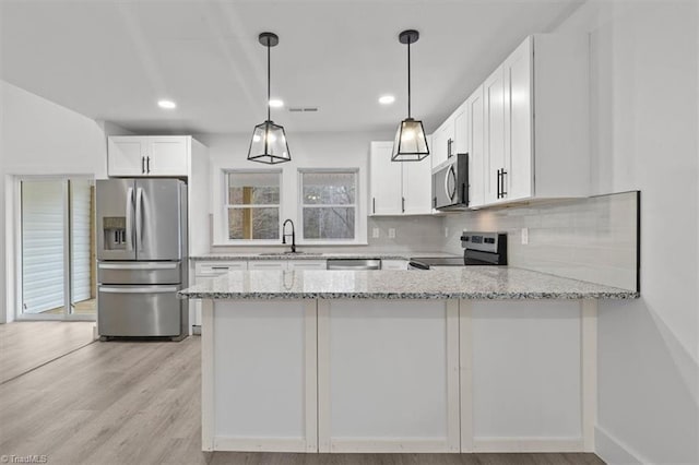 kitchen with a sink, backsplash, appliances with stainless steel finishes, a peninsula, and light stone countertops