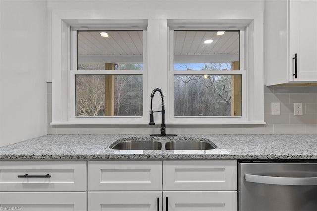 kitchen featuring stainless steel dishwasher, white cabinets, a healthy amount of sunlight, and a sink