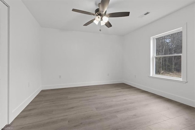 spare room with baseboards, wood finished floors, visible vents, and ceiling fan