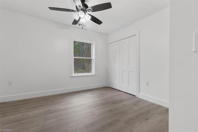 unfurnished bedroom featuring a closet, ceiling fan, baseboards, and wood finished floors