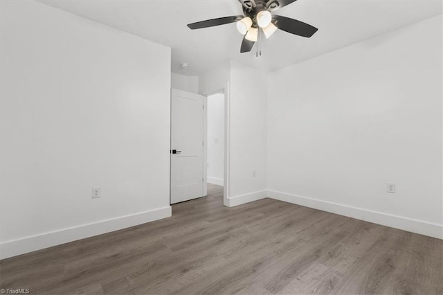 spare room featuring wood finished floors, baseboards, and ceiling fan