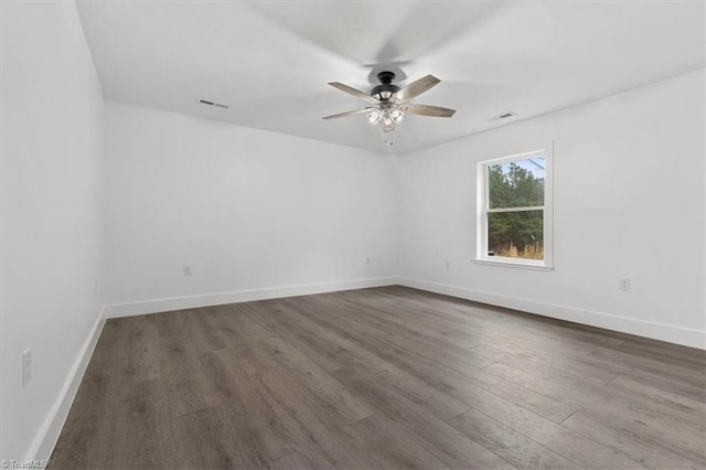 unfurnished room with dark wood-type flooring, baseboards, visible vents, and ceiling fan