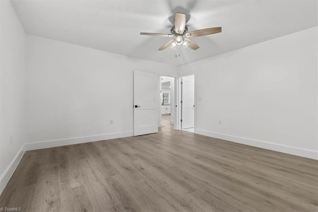 unfurnished room with baseboards, wood finished floors, and a ceiling fan