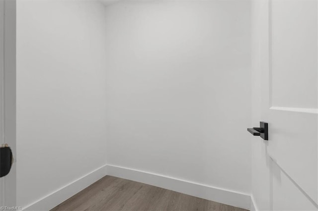 spare room with baseboards and wood finished floors