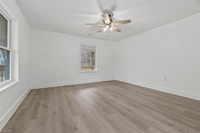 empty room featuring baseboards, wood finished floors, and a ceiling fan