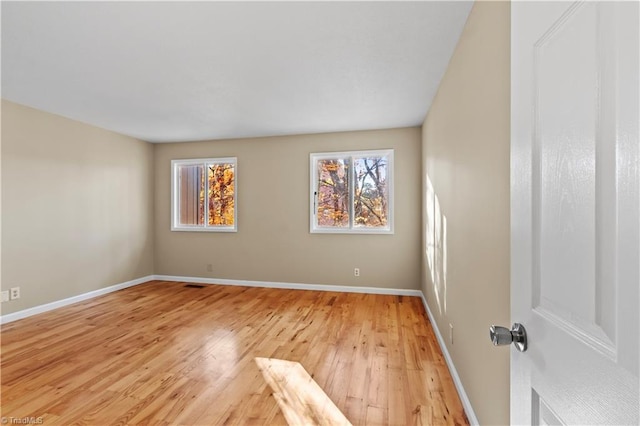 empty room with a wealth of natural light and light hardwood / wood-style flooring