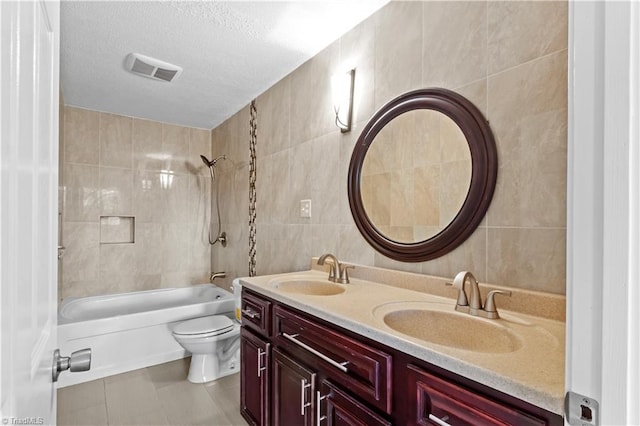 full bathroom with tiled shower / bath combo, double vanity, toilet, and tile walls