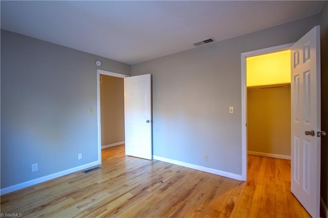 unfurnished bedroom featuring a closet, light hardwood / wood-style flooring, and a spacious closet