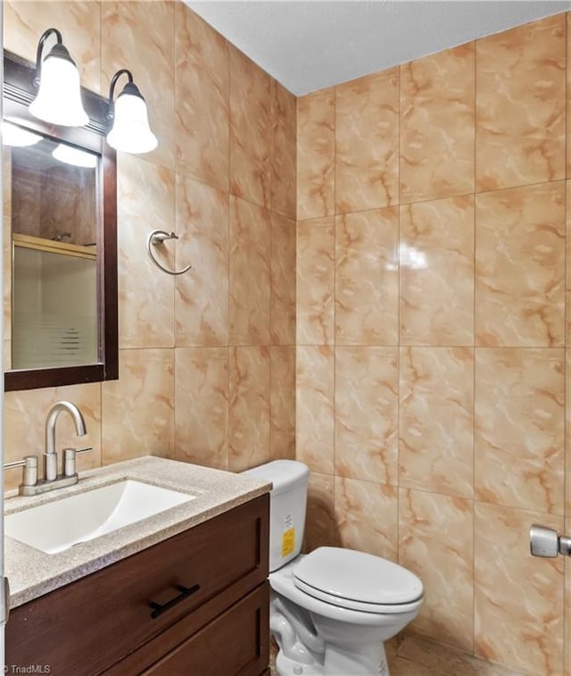 bathroom with tile walls, vanity, and toilet