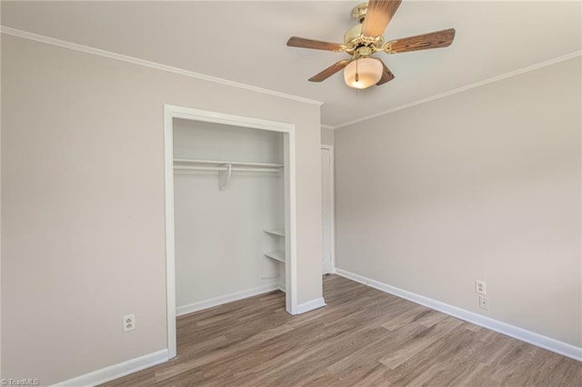 unfurnished bedroom featuring wood-type flooring, a closet, ceiling fan, and crown molding