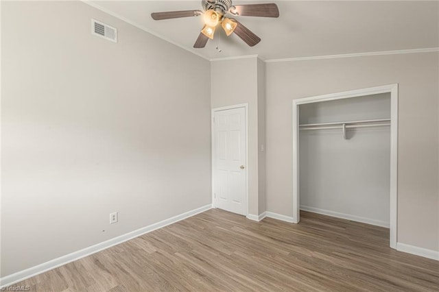 unfurnished bedroom featuring a closet, hardwood / wood-style flooring, ceiling fan, and ornamental molding