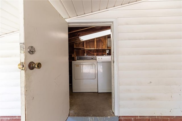 laundry room with wood walls and washer and clothes dryer