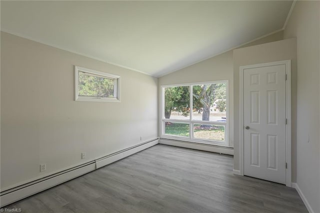 empty room with lofted ceiling, light hardwood / wood-style flooring, and a baseboard heating unit