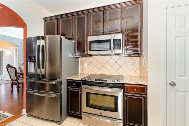4060 Tarmac Dr, Sophia, NC 27350 - kitchen featuring appliances with stainless steel finishes, arched walkways, light stone countertops, tasteful backsplash, and dark brown cabinets