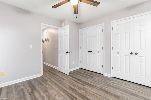 unfurnished bedroom with hardwood / wood-style flooring, ceiling fan, and multiple closets