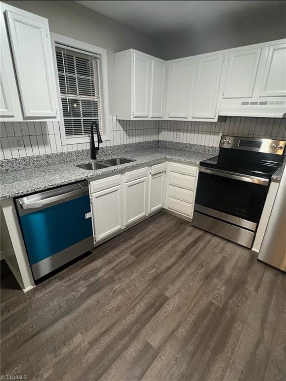 kitchen with white cabinets, sink, appliances with stainless steel finishes, dark hardwood / wood-style flooring, and light stone counters