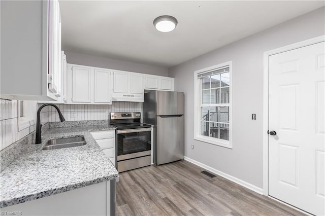 kitchen featuring white cabinetry, sink, light stone counters, light hardwood / wood-style flooring, and appliances with stainless steel finishes