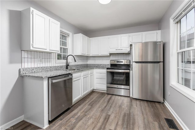 kitchen featuring backsplash, plenty of natural light, white cabinetry, and stainless steel appliances