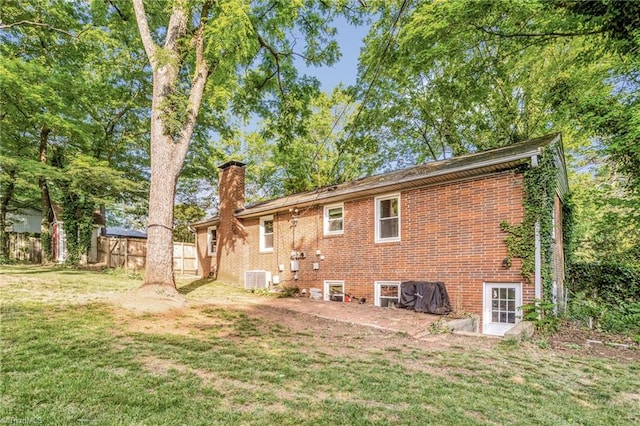 2703 W Cornwallis Dr, Greensboro, NC 27408 - rear view of house with a chimney, a lawn, brick siding, fence, and central AC