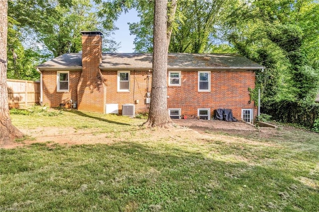 2703 W Cornwallis Dr, Greensboro, NC 27408 - back of property with a chimney, fence, central AC unit, a yard, and brick siding