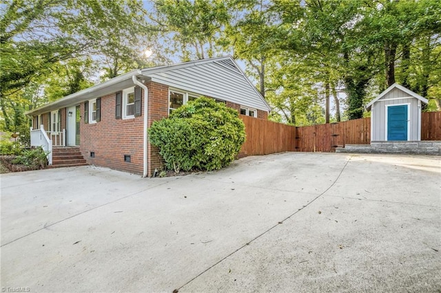 2703 W Cornwallis Dr, Greensboro, NC 27408 - view of home's exterior featuring crawl space, fence, an outdoor structure, a shed, and brick siding