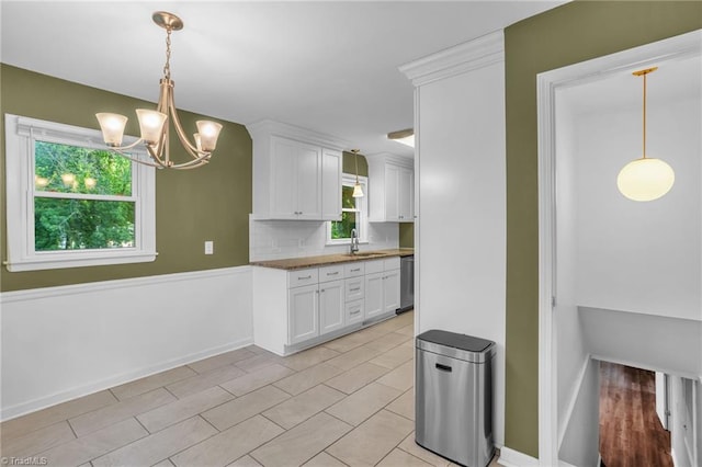 2703 W Cornwallis Dr, Greensboro, NC 27408 - kitchen featuring a sink, decorative light fixtures, baseboards, white cabinetry, and a notable chandelier