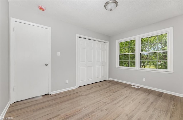 unfurnished bedroom with a closet, light hardwood / wood-style flooring, and a textured ceiling