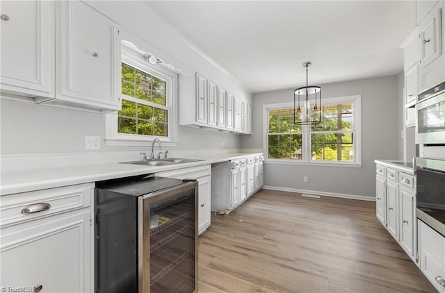 kitchen featuring a wealth of natural light, white cabinets, light hardwood / wood-style floors, and decorative light fixtures