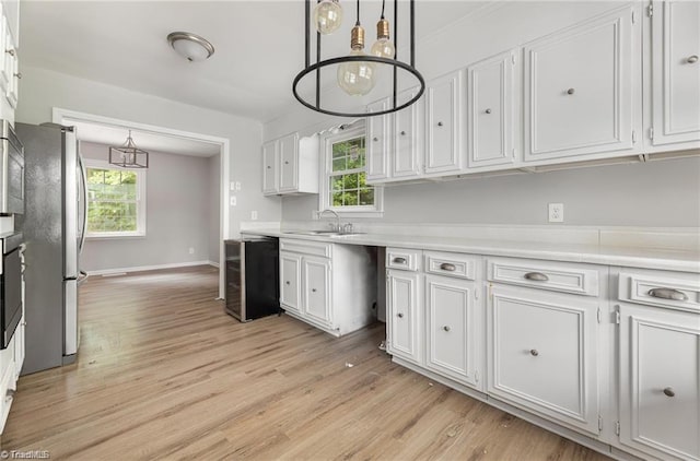 kitchen with white cabinets, appliances with stainless steel finishes, light hardwood / wood-style floors, and sink