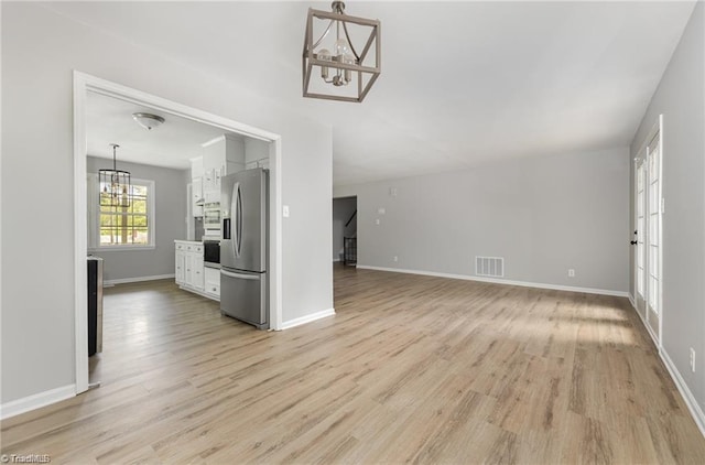 2725 New Walkertown Rd, Winston-Salem, NC 27105 - unfurnished living room with a chandelier, light wood-style floors, and baseboards