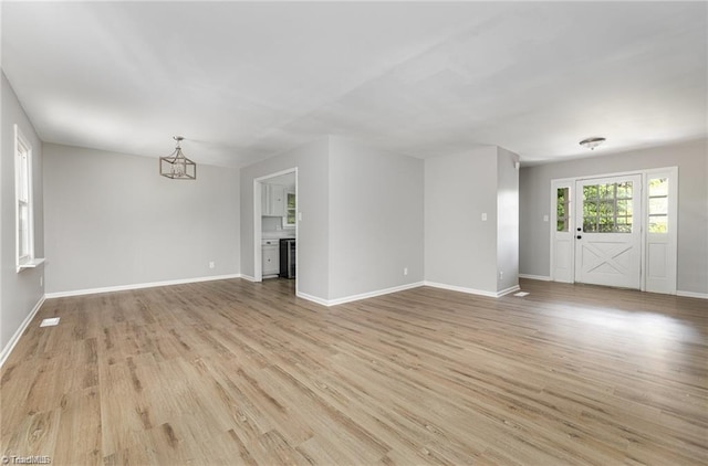 2725 New Walkertown Rd, Winston-Salem, NC 27105 - unfurnished living room with light wood finished floors, a chandelier, and baseboards