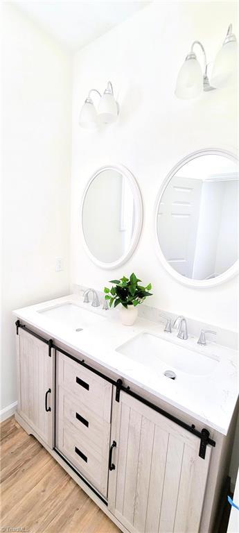 bathroom with double vanity and wood finished floors