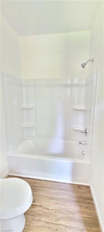 full bathroom with wood finished floors, tub / shower combination, toilet, and baseboards