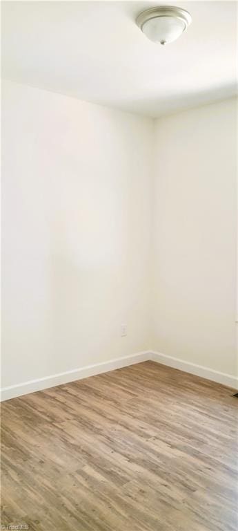 spare room featuring wood finished floors and baseboards