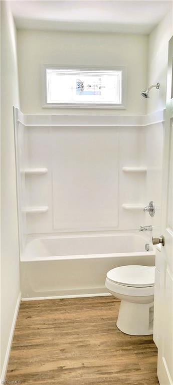 full bath with toilet, bathing tub / shower combination, healthy amount of natural light, and wood finished floors