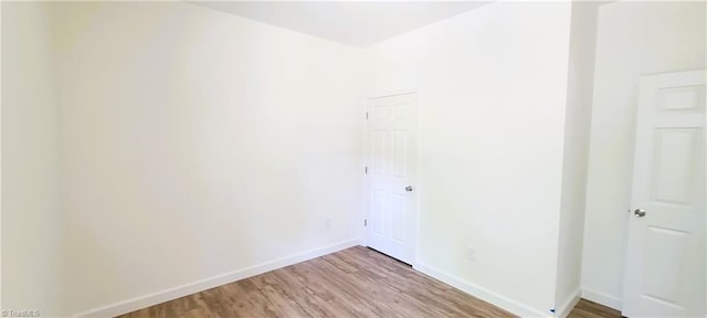 spare room featuring light wood-type flooring and baseboards
