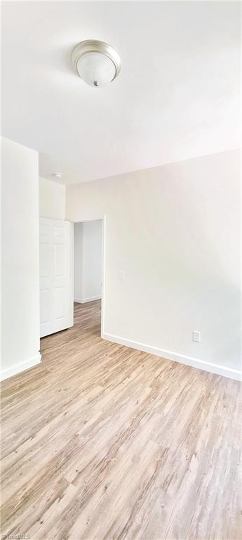 spare room with light wood finished floors and baseboards