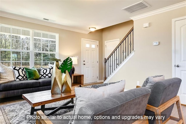 living room featuring visible vents, wood finished floors, baseboards, ornamental molding, and stairs