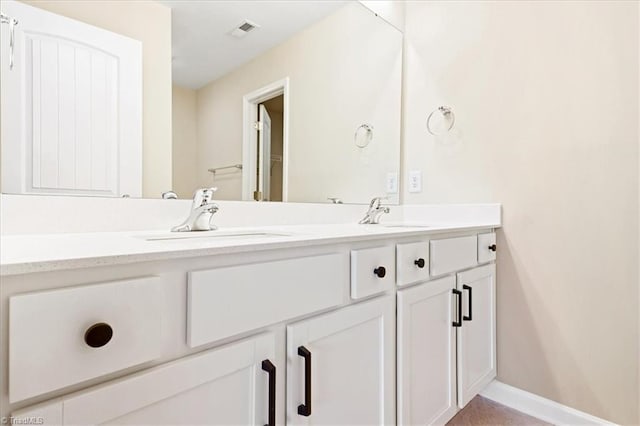 bathroom featuring a sink, baseboards, double vanity, and visible vents