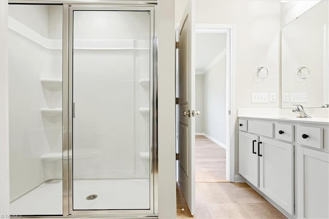 bathroom with crown molding, baseboards, a shower stall, and vanity