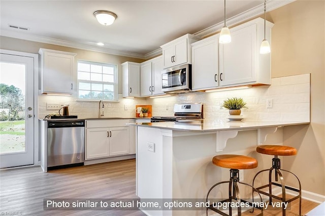 kitchen featuring a sink, light wood-style floors, a kitchen breakfast bar, stainless steel appliances, and visible vents