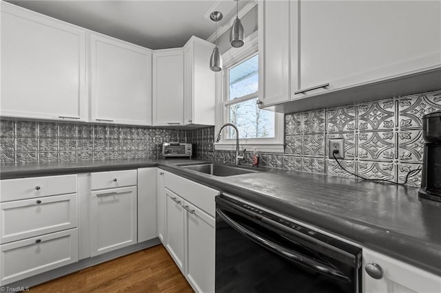 kitchen featuring black dishwasher, dark countertops, backsplash, white cabinetry, and a sink