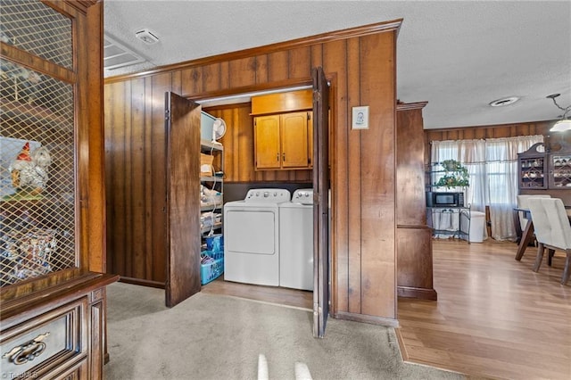 clothes washing area featuring cabinet space, ornamental molding, wooden walls, a textured ceiling, and independent washer and dryer