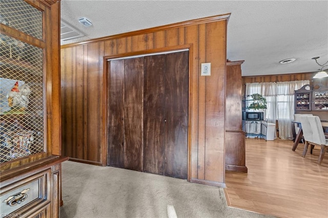 interior space with carpet flooring, wooden walls, and a textured ceiling