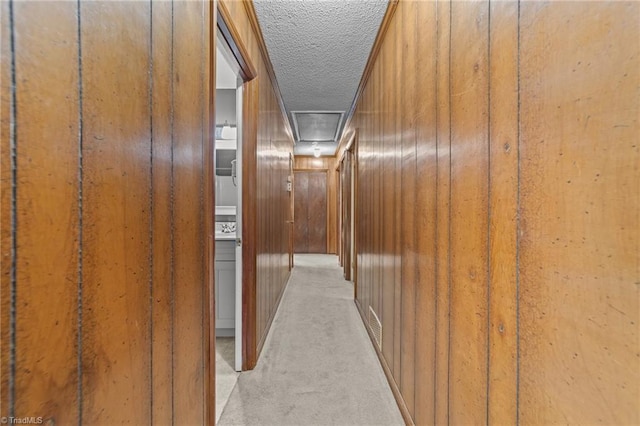 hallway featuring a textured ceiling and light colored carpet