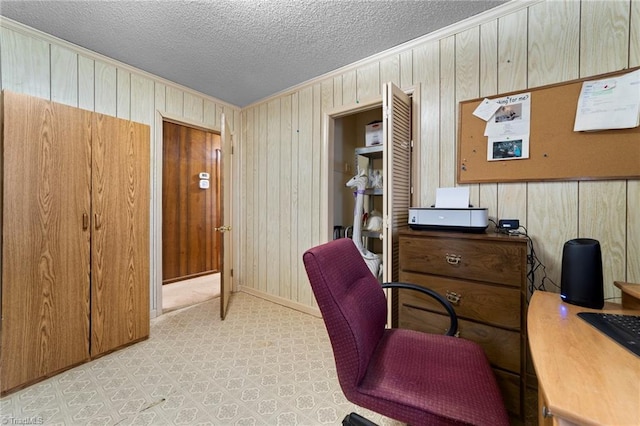 office area with crown molding, wood walls, a textured ceiling, and baseboards